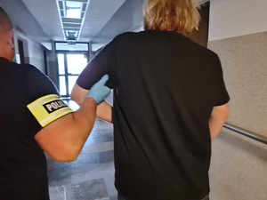 Zatrzymany podczas doprowadzenia trzymany pod rękę przez policjanta