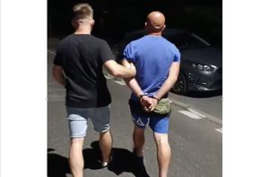 Nieumundurowany policjant doprowadza zatrzymanego ulicą