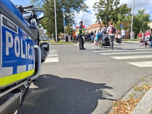 Policjant zabezpiecza skrzyżowanie przez które przechodzą pielgrzymi
