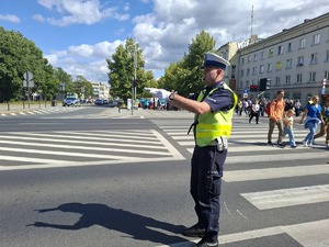 Policjant na skrzyżowaniu wykonuje gest rękami w stronę kierujących