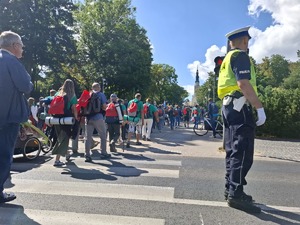 Policjant zabezpiecza przejście pielgrzymów przez jezdnię