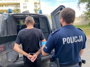 Policjant doprowadza zatrzymanego do radiowozu