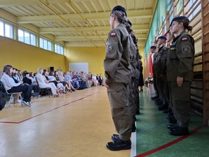 Klasa mundurowa stoi w dwuszeregu na sali gimnastycznej podczas uroczystości