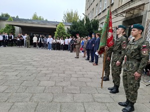 Służby mundurowe stoją w szeregu na placu wśród uczniów
