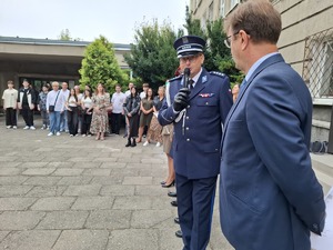 Komendant stoi obok mężczyzny i przemawia do mikrofonu