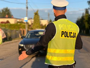 Policjant stoi przed pojazdem, który zatrzymał do kontroli