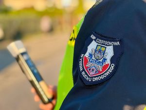 Urządzenie do badania stanu trzeźwości trzymane w ręce, a a rękawie munduru emblemat z napisem Wydział Ruchu Drogowego Komendy Miejskiej Policji Częstochowa