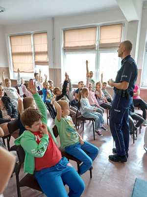 Policjant rozmawia z uczniami w szkolnej sali.