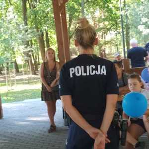 Policjantka zwrócona w stronę dzieci podczas prelekcji w plenerze pod altaną