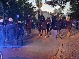 Policjanci na koniach wspólnie z drużyną policyjna zabezpieczają drogę przemarszu kibiców na stadion