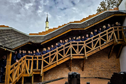 Policjanci pozują do wspólnego zdjęcia stojąc za balustrada budynku