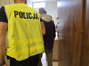 Policjant doprowadza zatrzymanego do pomieszczenia służbowego