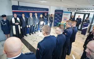 Zgromadzeni uczestnicy spotkania podczas uroczystości stoją w korytarzu przed aulą
