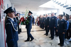 Delegacja policjantów składa wiązankę kwiatów przed płytą
