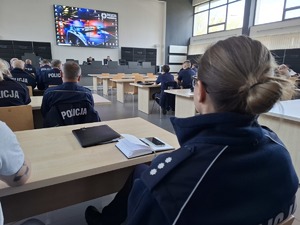 Policjantka podczas wykładu siedzi w auli wśród policjantów