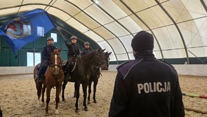 Policjant przygląda się ćwiczeniom które wykonuje policjant na koniu