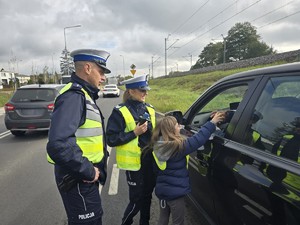 Dziecko w obecności policjantów wręcza jabłko kierującemu