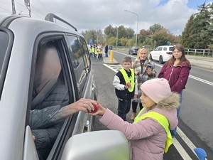 Dziecko wręcza jabłko kierującemu