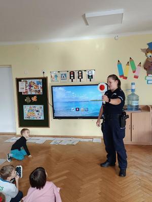 Policjantka prezentuje dzieciom tarcze do zatrzymywania pojazdów