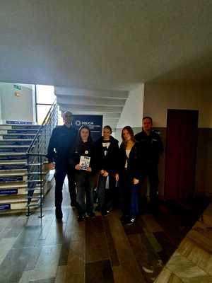 Policjant pozuje do zdjęcia z młodzieżą, która stoi przy schodach