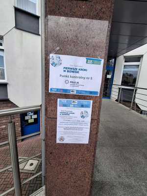 Plakaty zawieszone na filarze budynku