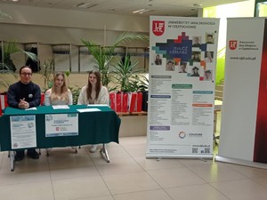 Dwie kobiety i mężczyzna siedzą przy stoliku przy banerze