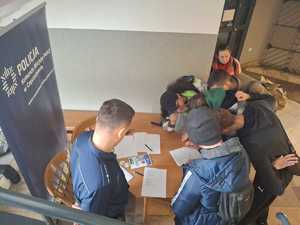 Młodzież zainteresowana stoiskiem policyjnym przy którym siedzi policjant