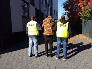 Nieumundurowani policjanci doprowadzają zatrzymanego męzczyznę