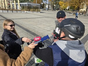 Dziennikarze rozmawiają z mężczyzną, który ma na głowie kask ochronny