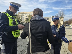 Policjanci rozmawiają z kobietą, która stoi przy hulajnodze