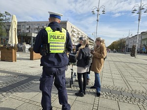 Dziennikarze rozmawiają z mężczyzną na hulajnodze, obok stoi policjant