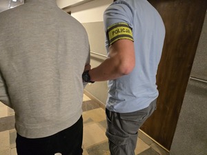 Nieumundurowany policjant doprowadza zatrzymanego