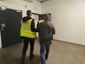 Policjanci doprowadzają zatrzymanego mężczyznę
