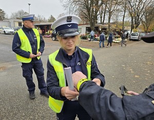 Policjantka zakłada opaskę odblaskową na rękę mężczyzny