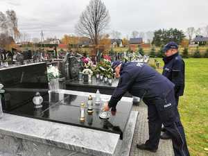 Policjant składa znicz na grobie