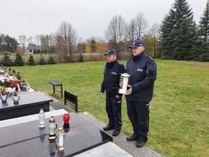 Policjanci stoją ze zniczem przy grobie