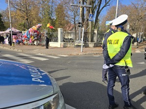 Policjantka przy radiowozie patroluje drogę przy cmentarzu