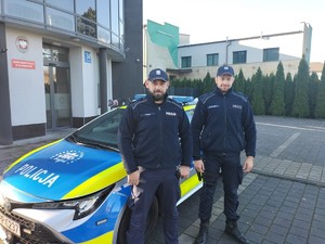 Patrol dzielnicowych stoi przed komisariatem przy radiowozie