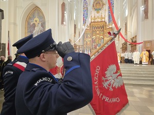 Policjant oddaje honor podczas mszy w kościele, sztandar komendy pochylony