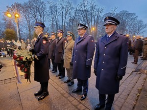 Delegacja mundurowych stoi z kwiatami