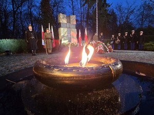 Palący się znicz na tle pomnika