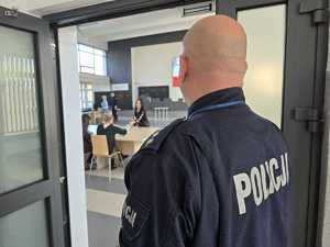 Policjant stoi przy wejściu do auli