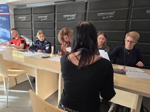 Kobieta siedzi przed osobami przy stoliku i