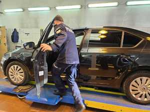 Policjant wsiada do samochodu, który znajduje się w warsztacie samochodowym