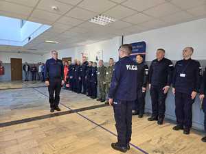 Policjanta wśród uczestników ćwiczeń składa meldunek komendantowi