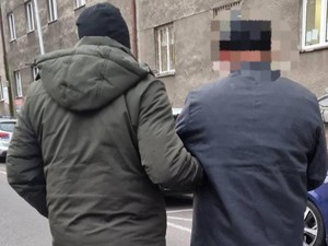 Nieumundurowany policjant prowadzi zatrzymanego przez ulicę