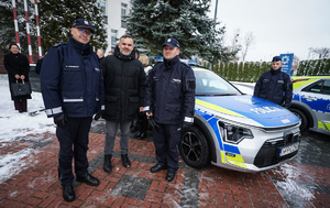 Policjanci z mężczyzna pozują do zdjęcia na tle radiowozu
