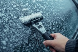 Oblodzona szyba i ręka ze skrobaczką przy niej