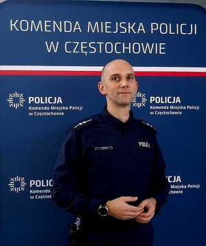 Policjant w mundurze pozuje do zdjęcia przy ściance