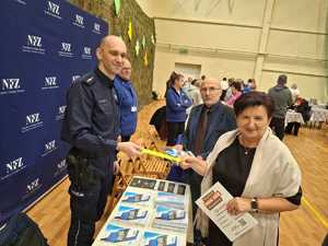 Policjant wręcza opaskę odblaskową seniorce